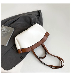 Macro detail of white and brown leather tote bag with H-stitch and metal bottom rivets