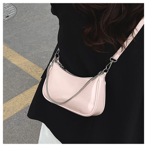 Close-up of pale pink patent leather half-moon shoulder bag with silver chain detail