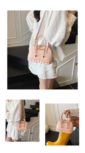 Detail of pink patent leather shell bag featuring golden rivets and chain decorations