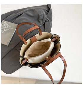 Detail view of scalloped edge tote bag with brown leather handles and canvas inner pouch