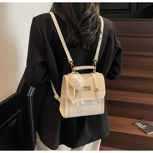 Close-up of a small cream woven backpack with PVC splicing and a plush charm on a model