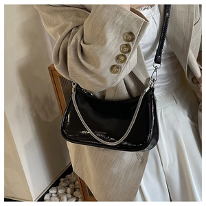 Detail of glossy black patent leather crescent bag with chic silver chain and strap