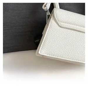 Détail du sac à main blanc à motif litchi montrant les coutures fines et la boucle en métal