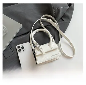 Mini sac à main blanc en cuir grainé comparé à la taille d'un téléphone portable