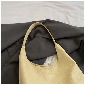 Detailed close-up of cream hobo bag with natural lychee grain texture and wide strap