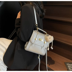Silver woven texture backpack with golden lock and plush charm on black blazer