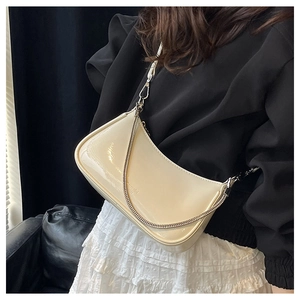 Macro shot of a cream glossy faux leather underarm bag with sleek metal chain detail