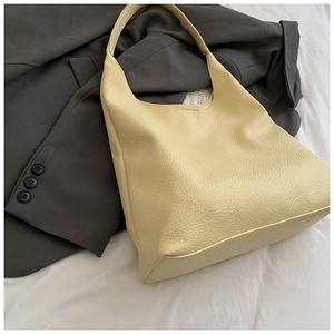 Detailed macro view of cream lychee texture leather on a stylish minimalist hobo bag