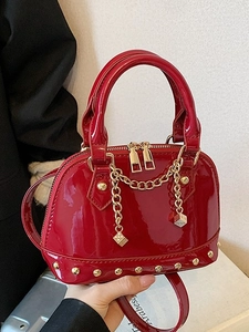 Red patent leather shell bag with gold rivet accents and dice chain charm