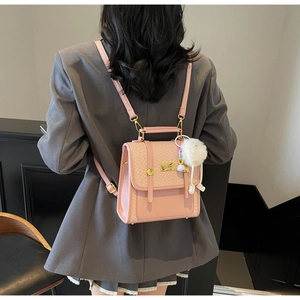Detail of pink mini backpack with woven texture flap and soft white pom-pom pendant