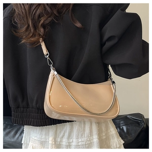 Close-up of beige patent leather crescent bag with silver chain and thin strap details