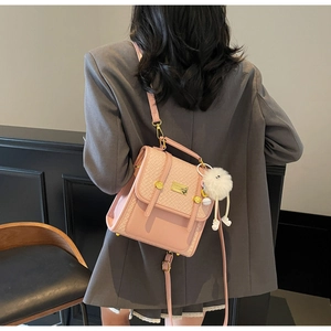 Detail of pink PU leather backpack featuring embossed weave texture and fluffy pompom