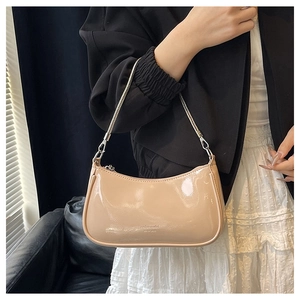 Detailed close-up of beige patent leather shoulder bag with silver chain strap and mirror finish