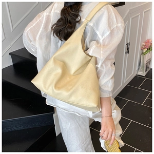 Detailed view of cream leather tote bag with soft lychee texture on model's shoulder