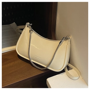 Detailed close-up of cream patent leather baguette bag with silver chain and embossed logo