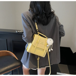 Fashionable bright yellow backpack with woven texture and white pompom on a female model