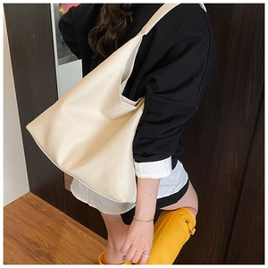 Detail of a large cream tote bag with lychee texture and wide shoulder strap