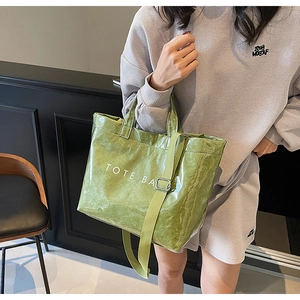 Detail of avocado green tote bag featuring unique glossy crinkled texture and TOTE BAG text