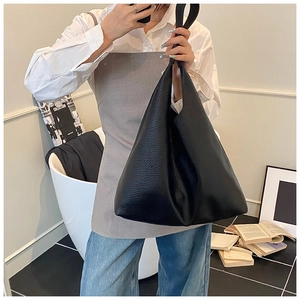 Detailed view of black litchi grain leather texture on a minimalist large tote bag