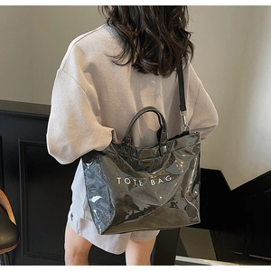 Close-up of black glossy tote bag with white TOTE BAG print and nylon shoulder strap