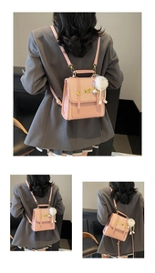 Detail of pink embossed backpack with golden metal buckle and white plush charm accessory