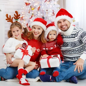 Family at Christmas tree with red plaid gift tags featuring Let it Snow and Peace text