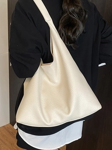 Chic cream-white large capacity hobo bag in pebbled leather worn by a model