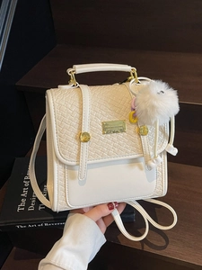 White leather tote bag with woven texture lid, gold hardware and plush ball charm