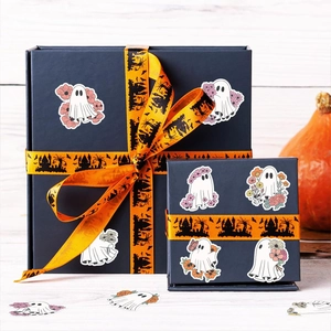Close-up of cute Halloween floral ghost stickers on a blue gift box with festive ribbon