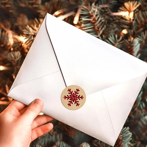 Close-up of buffalo plaid snowflake sticker sealing a gift envelope on festive background