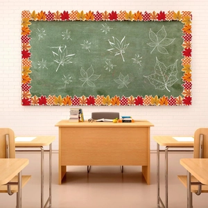 Close-up of wavy autumn maple leaf borders and orange plaid patterns on a green blackboard