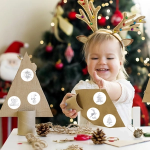 Fillette utilisant des autocollants de Noël avec flocons et rennes pour le bricolage