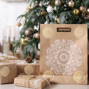 Close-up of gold foil Merry Christmas seals on kraft gift bags with snowflake patterns
