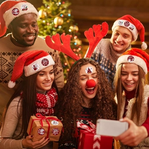 Friends using Merry Christmas round stickers on hats and gift boxes in a festive setting