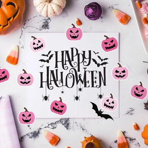 Close-up of pink Halloween pumpkin and bat stickers on marble background with greeting card
