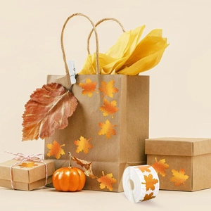 Roll of holographic autumn maple leaf stickers applied on brown paper gift packaging
