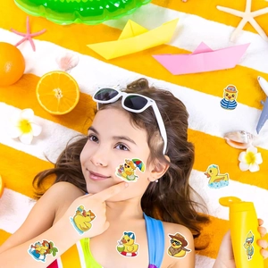 Girl on beach towel showing various cartoon duck temporary stickers in summer sun