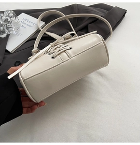 Detail of cream white faux leather handbag with lace-up side design and metal eyelets