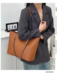 Detail showing the large capacity and fine white stitching on a brown leather tote bag