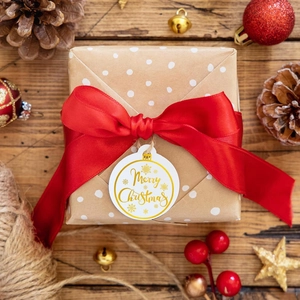 Close-up of brown gift box with red ribbon and gold Merry Christmas sticker tag