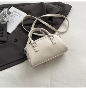 Detail of off-white leather Boston bag with round handles and adjustable shoulder strap