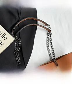 Detail of long brown leather shoulder strap with black metal chain and fine edge oiling