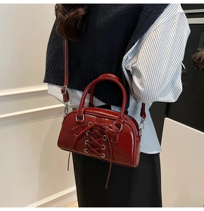 Detail of burgundy glossy Boston bag with lace-up eyelets and dual handles