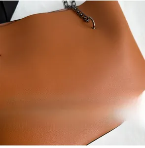Close-up of brown pebbled leather texture with gunmetal chain strap detail