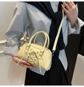 Close-up of cream yellow crossbody bag with corset-style bow detail and silver hardware