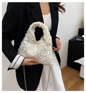 Detailed view of a white sequined handbag with silver chain strap on a stylish model