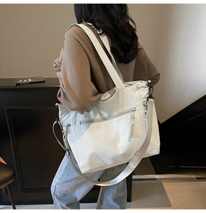 Detail view of large nylon tote bag with functional zippers and woven cord pulls