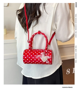 Close-up of red polka dot barrel bag with pearl heart and lace bow detail