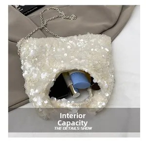 Detail view of the interior capacity showing a phone and cosmetics in the sequin bag
