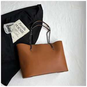 Close-up of brown faux leather tote bag with metal chain strap and minimalist design